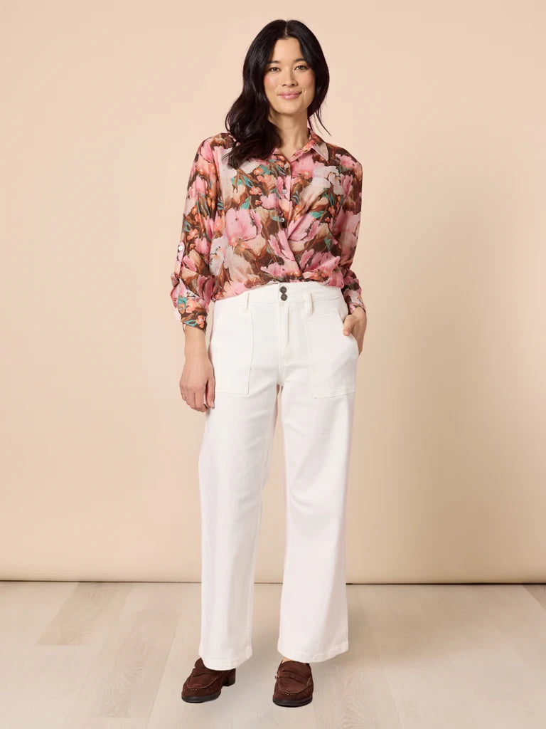 Image of Woman wearing a Gordon Smith floral blouse and white pants against a beige background