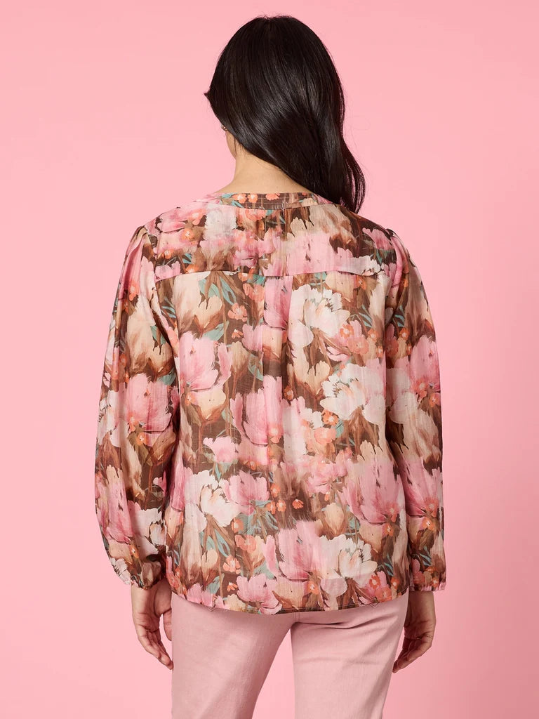 Image of Woman wearing a Gordon Smith floral blouse with a pink background
