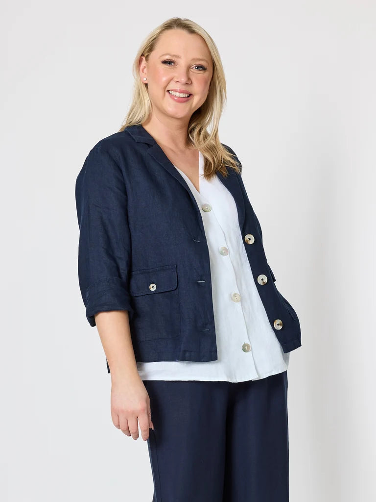Image of A woman modeling a Gordon Smith navy blue linen-blend blazer with gold-tone buttons, worn over a white top and navy pants, against a light gray studio background.