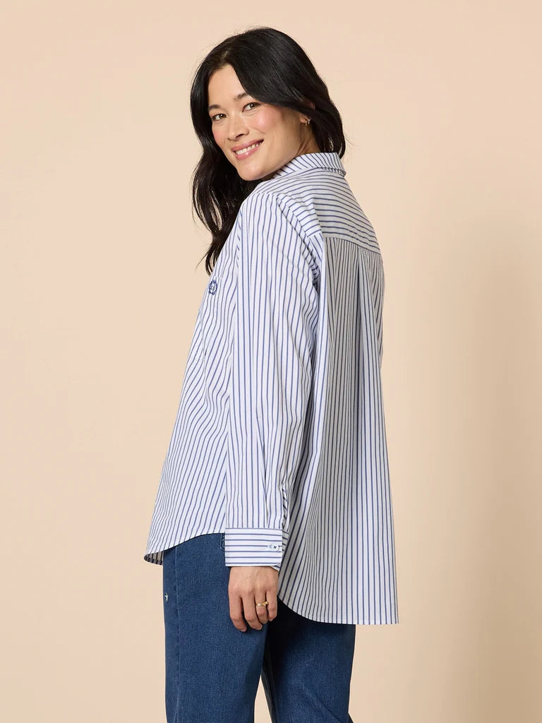Woman wearing a Gordon Smith striped shirt and blue jeans on a beige background