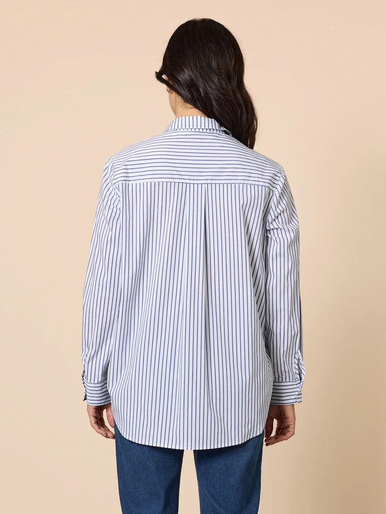 Woman wearing a Gordon Smith blue and white striped shirt on a beige background