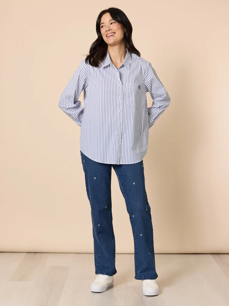 Image of Woman wearing a Gordon Smith blue and white striped shirt and blue jeans against a beige background