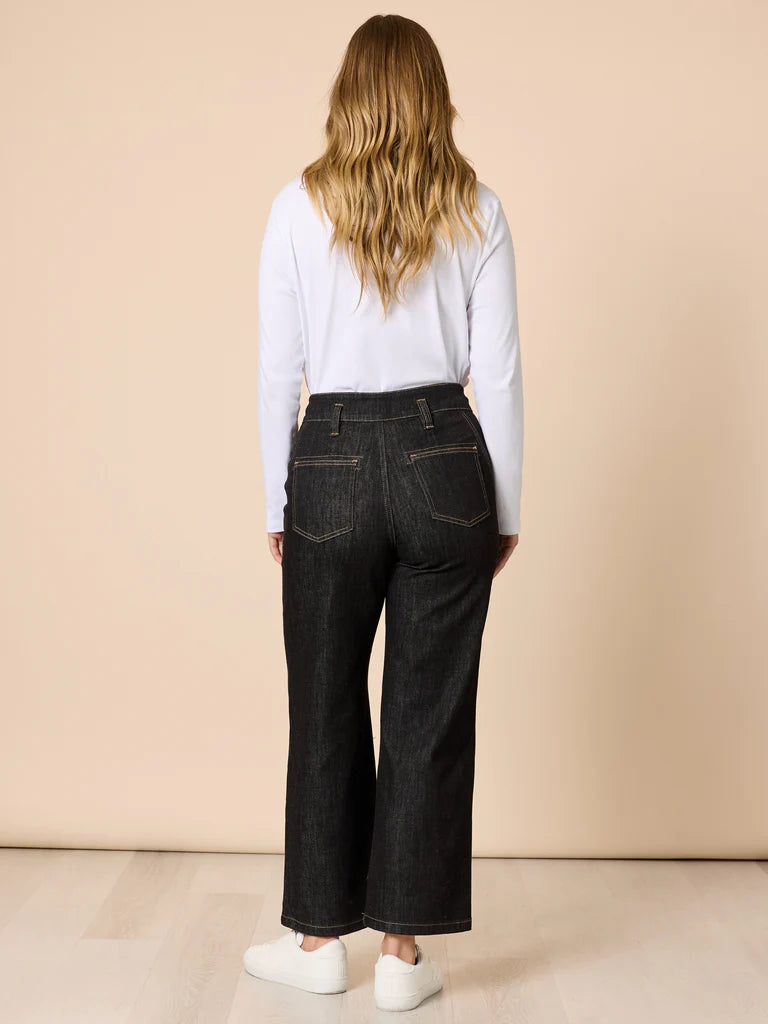 Woman wearing Gordon Smith dark jeans and a light blue shirt against a beige background
