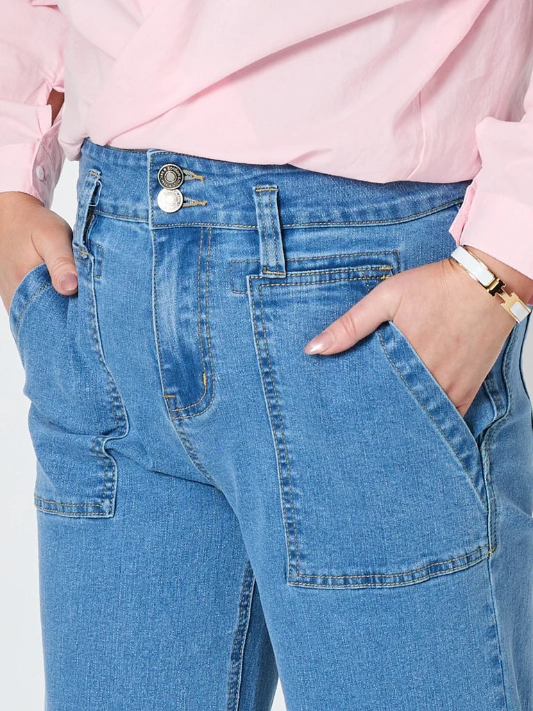 Image of Close-up of a woman wearing Gordon Smith light blue denim jeans with a pink shirt tucked into the waistband, showing the back pocket area and hands in the pockets.