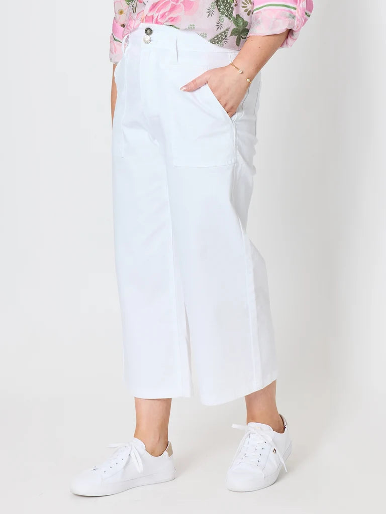Image of Gordon Smith white cropped wide-leg pants with side slits, shown on a model wearing a pink floral top and white sneakers against a light gray studio background.