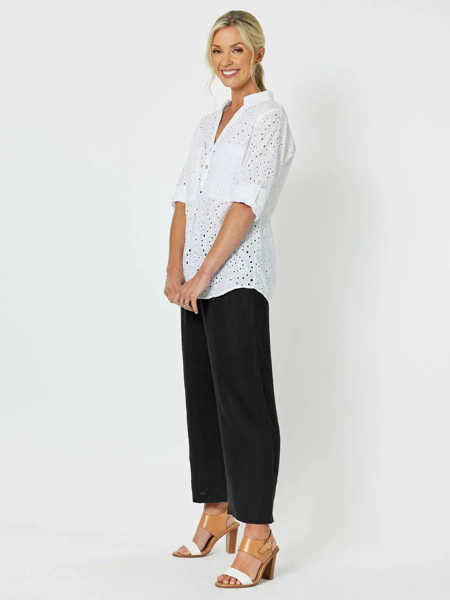 Woman wearing a white blouse with Gordon Smith black polka dots and black pants on a white background