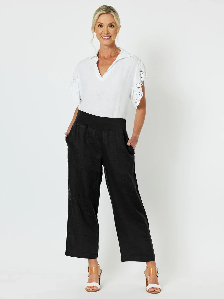 Image of Woman wearing a white blouse with lace sleeves and Gordon Smith black pants on a white background