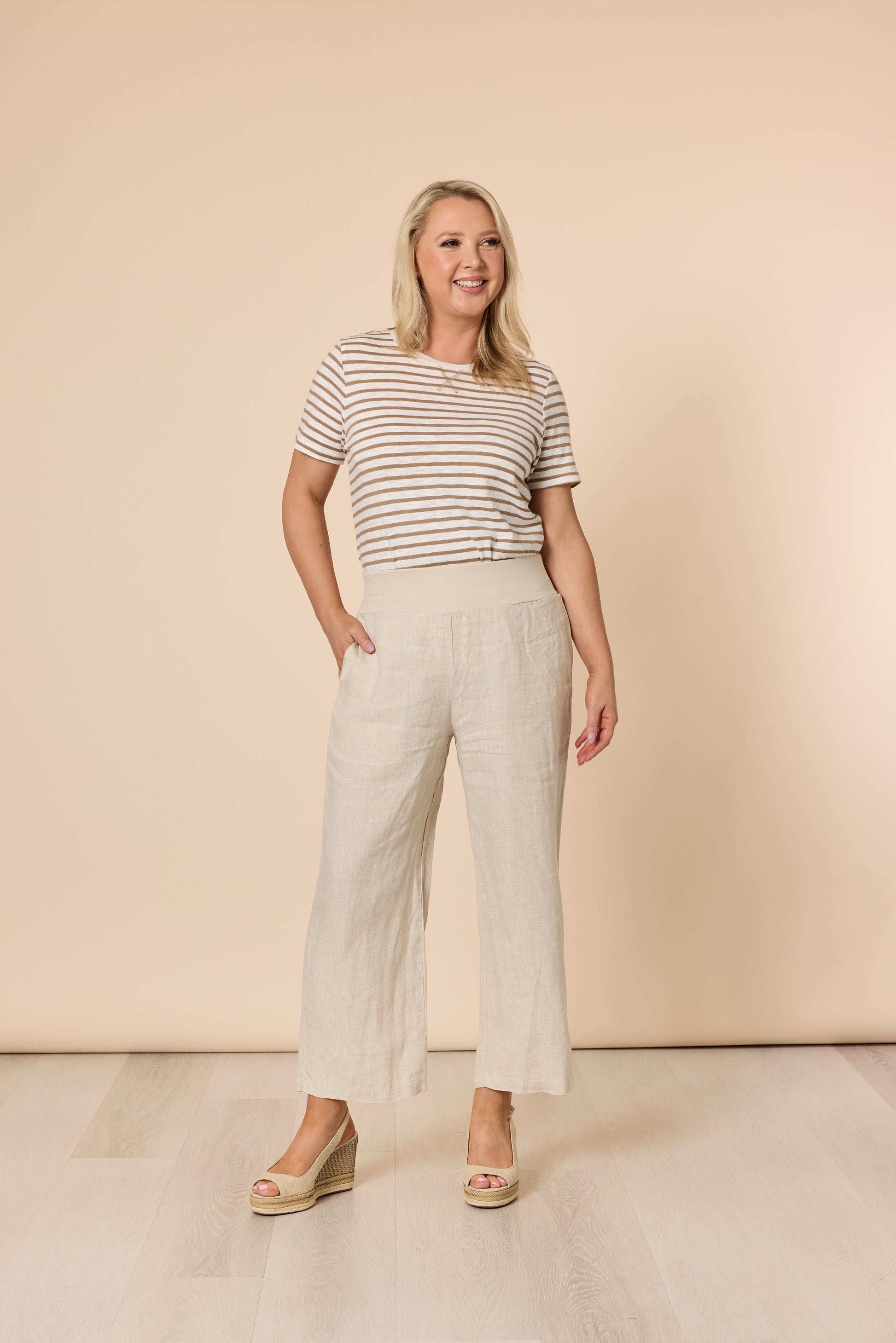 Woman wearing a striped shirt and Gordon Smith beige pants against a beige background