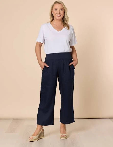 Image of Woman wearing a white top and Gordon Smith navy wide-leg pants against a beige background