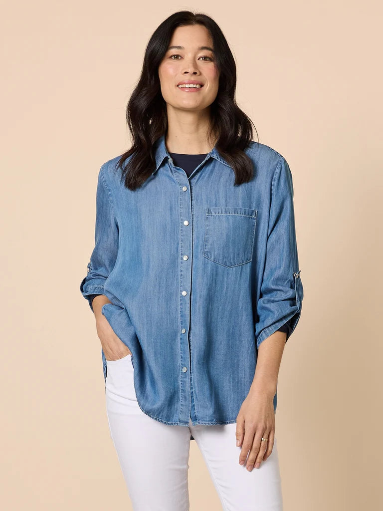 Woman wearing a Gordon Smith blue denim shirt and white pants against a beige background