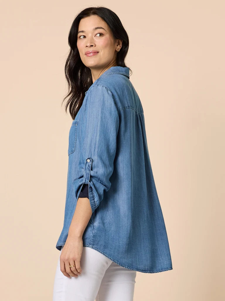 Image of Woman wearing a Gordon Smith blue denim shirt with rolled-up sleeves on a beige background