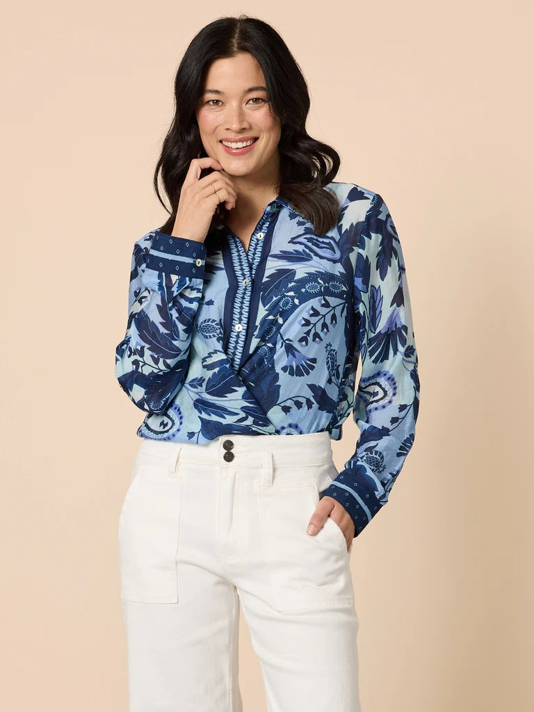 Collection of Woman wearing a Gordon Smith blue floral blouse and white pants against a beige background in a gallery layout