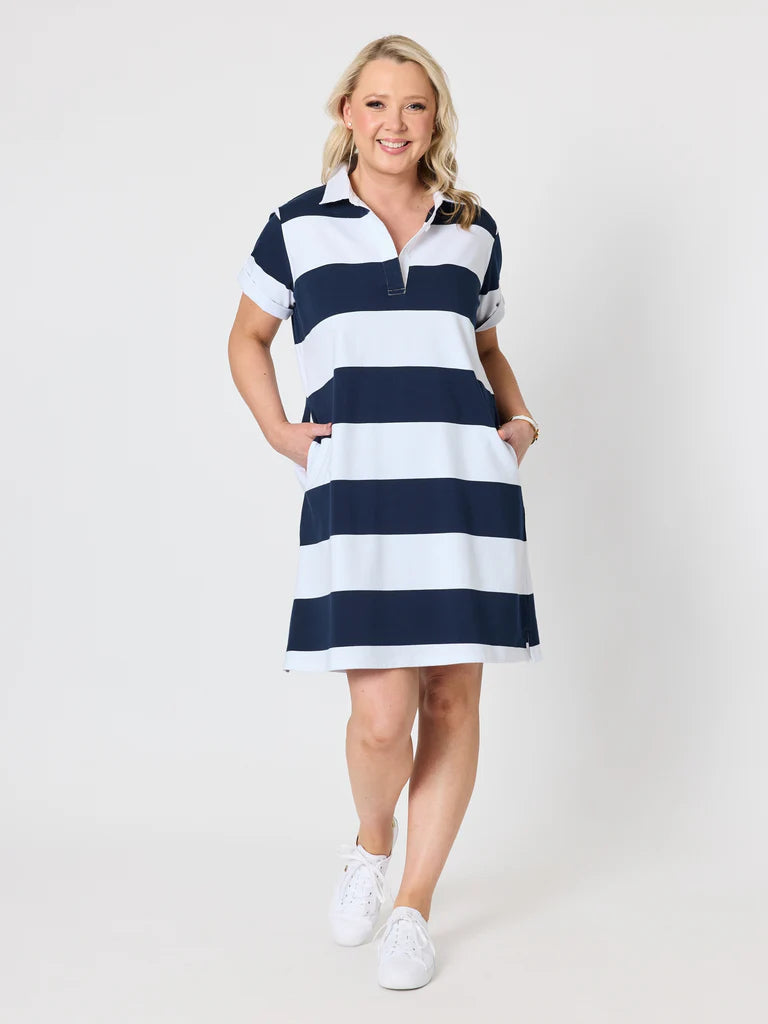 Image of A woman modeling a Gordon Smith short-sleeve polo dress with horizontal navy blue and white stripes, paired with white sneakers, against a light gray studio background.