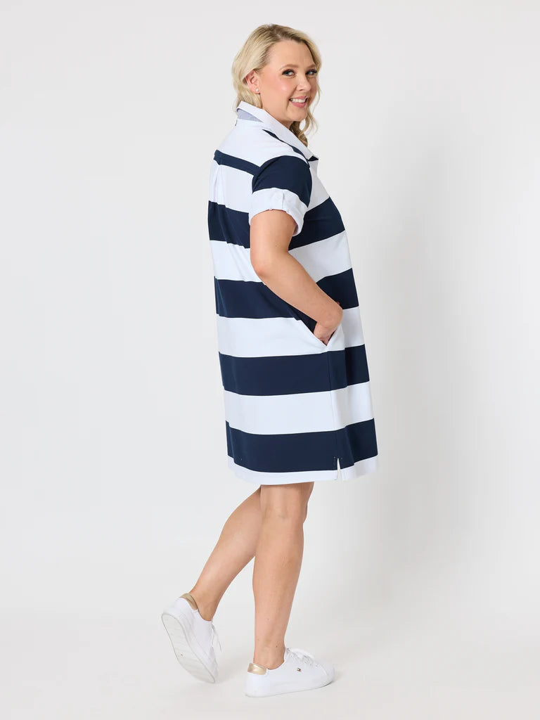A woman modeling a Gordon Smith short-sleeve polo dress with horizontal navy blue and white stripes, paired with white sneakers, against a plain white studio background.