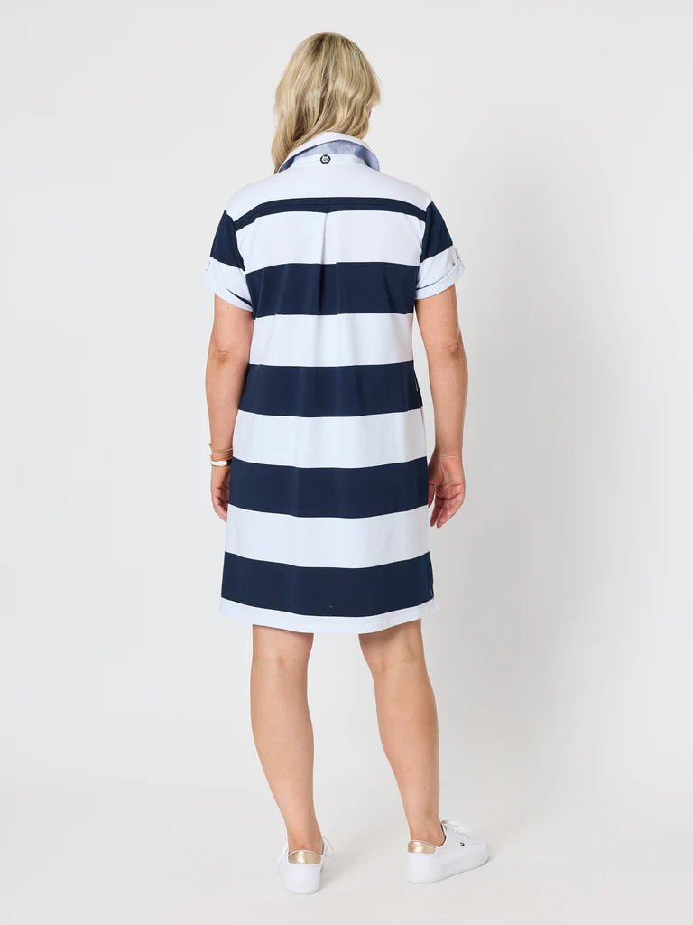 A woman viewed from the back wearing a Gordon Smith short-sleeve polo dress with horizontal navy blue and white stripes, paired with white sneakers, against a light gray studio background.