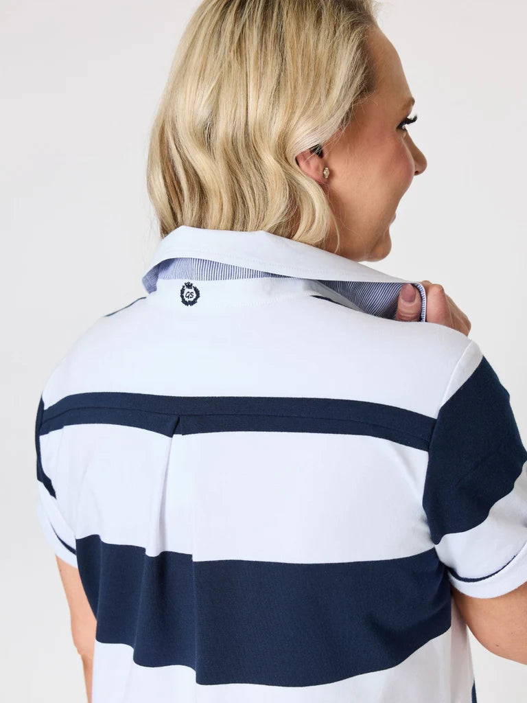 A woman shown from the back wearing a Gordon Smith short-sleeve polo dress with bold horizontal navy and white stripes. The shirt features a classic collar with a small circular logo patch on the inside neck label.