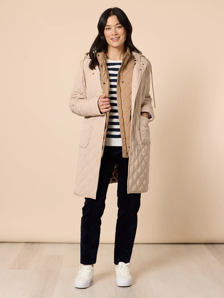 Image of Woman wearing a Gordon Smith beige quilted coat over a striped sweater with a beige background