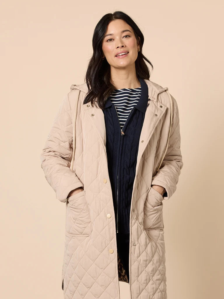 Woman wearing a Gordon Smith beige quilted coat against a beige background