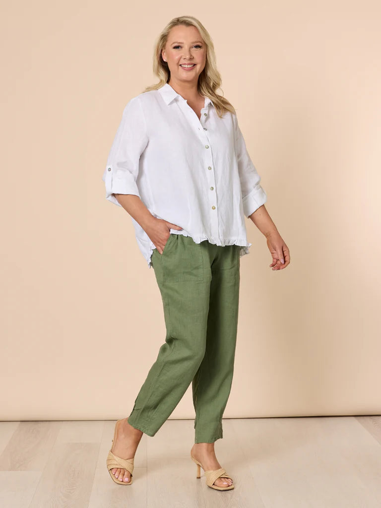 Woman wearing a white shirt and Gordon Smith green pants on a beige background