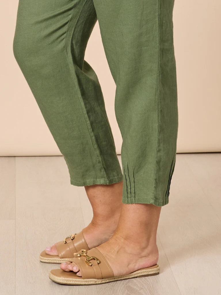 Women wearing Gordon Smith green pants and tan sandals on a beige background