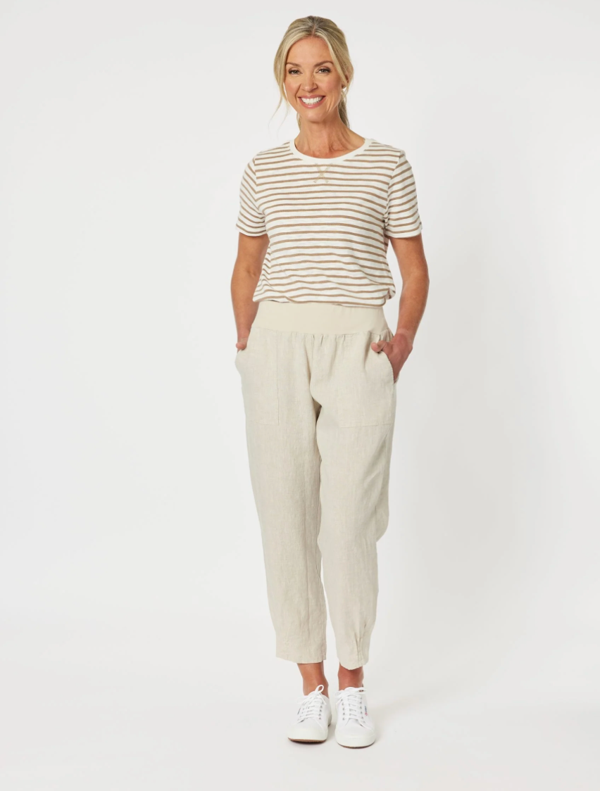 Woman wearing a striped shirt and Gordon Smith beige pants on a white background
