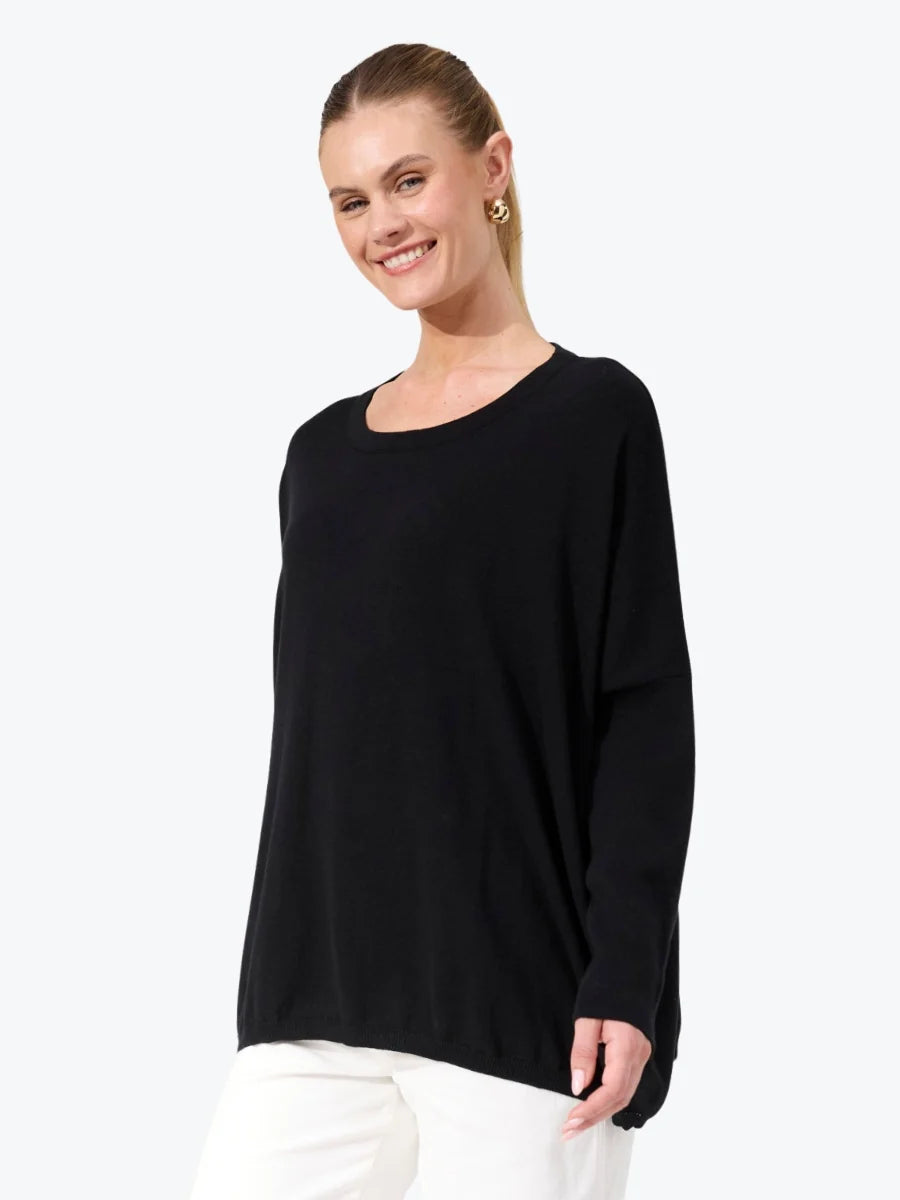Image of Woman wearing black Haven knit paired with white jeans on a plain background 
