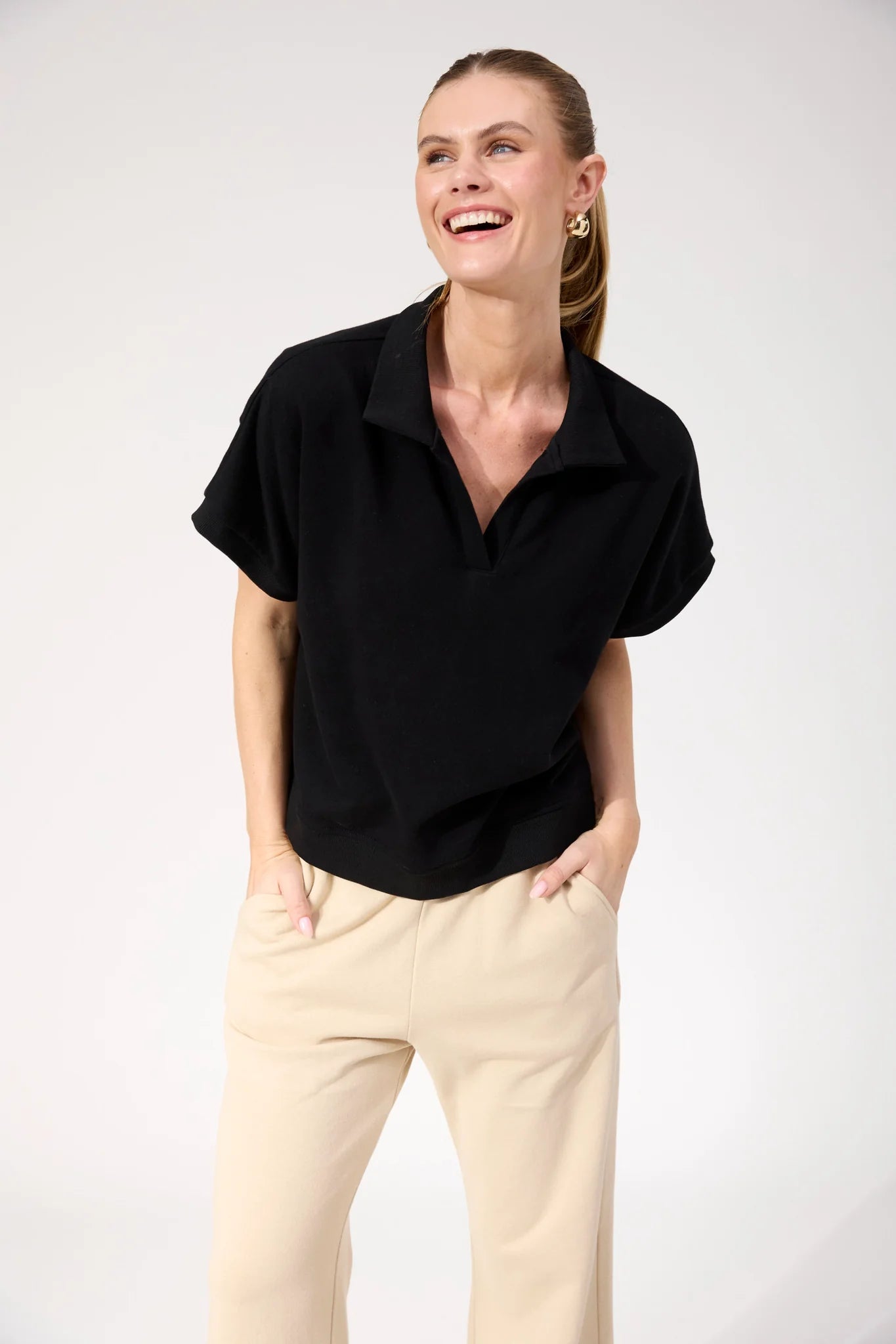 Image of Woman wearing Haven Boston Crop Sweat top in black paired with pants on a plain background 
