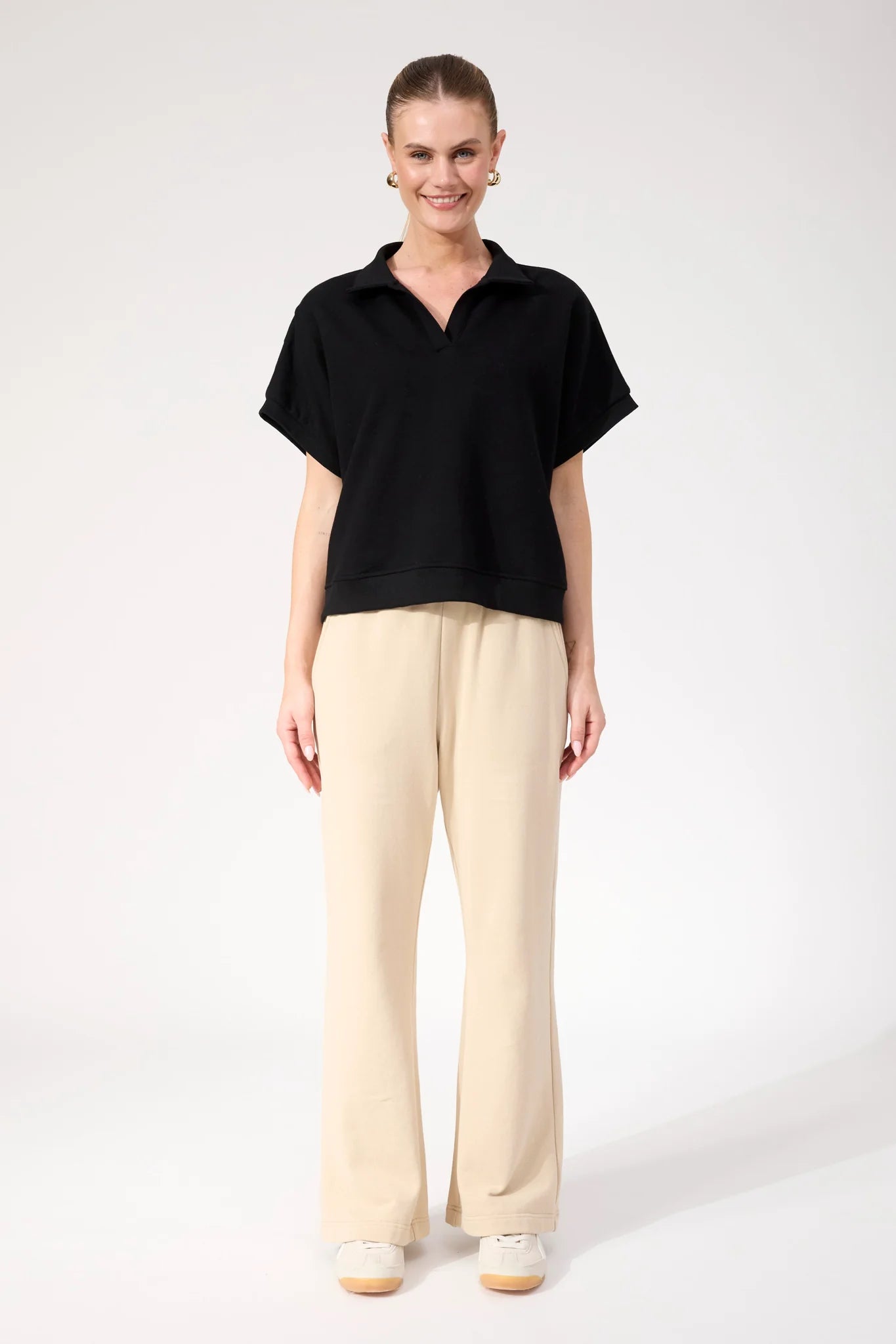 Image of Woman wearing Haven Boston Crop Sweat top in black paired with pants on a plain background 