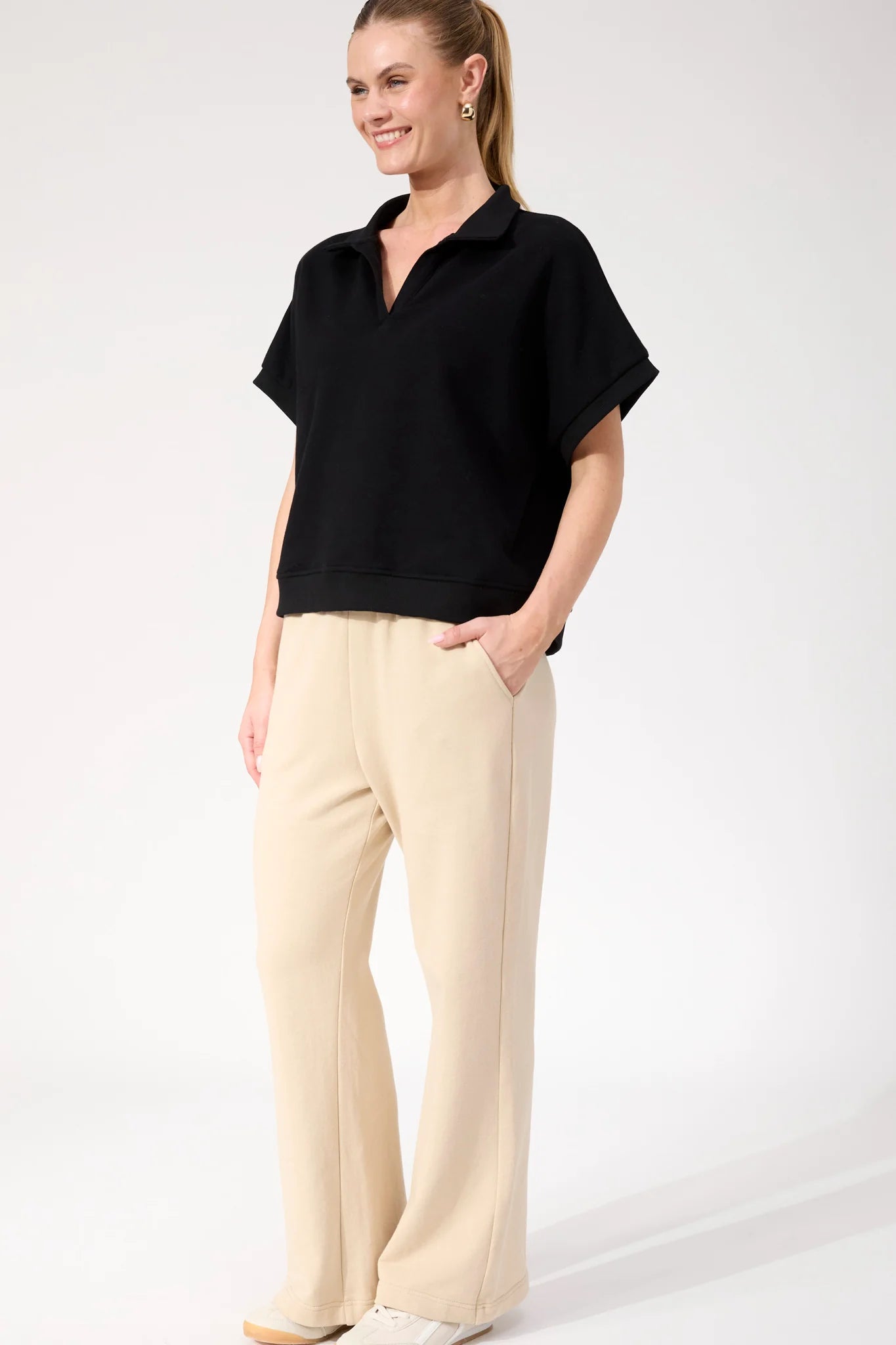 Image of Woman wearing Haven Boston Crop Sweat top in black paired with pants on a plain background 