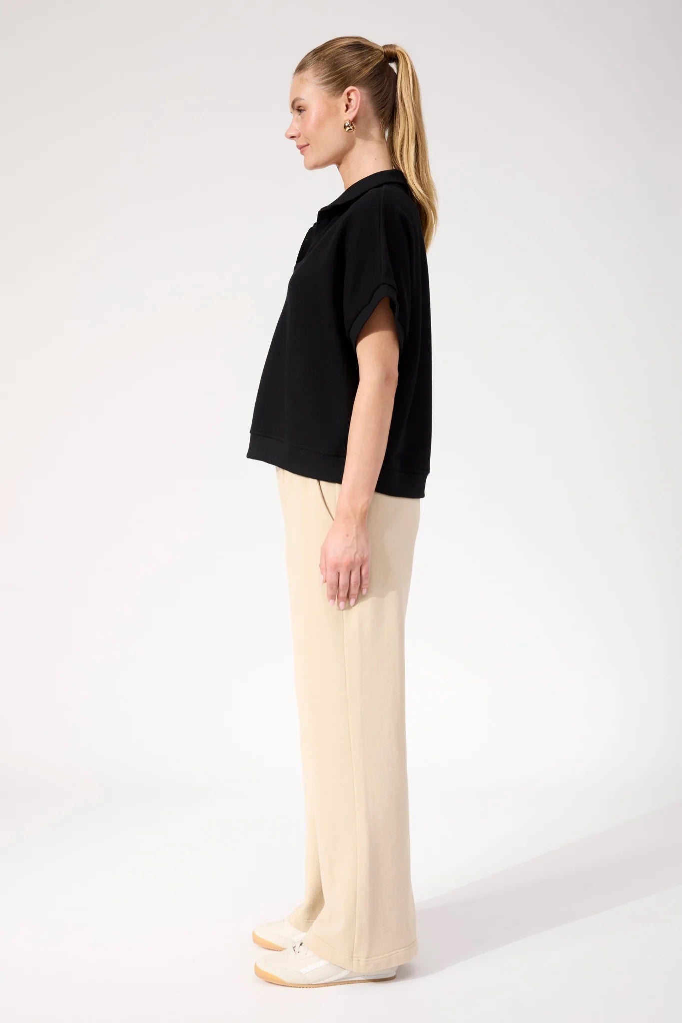 Image of Woman wearing Haven Boston Crop Sweat top in black paired with pants on a plain background 