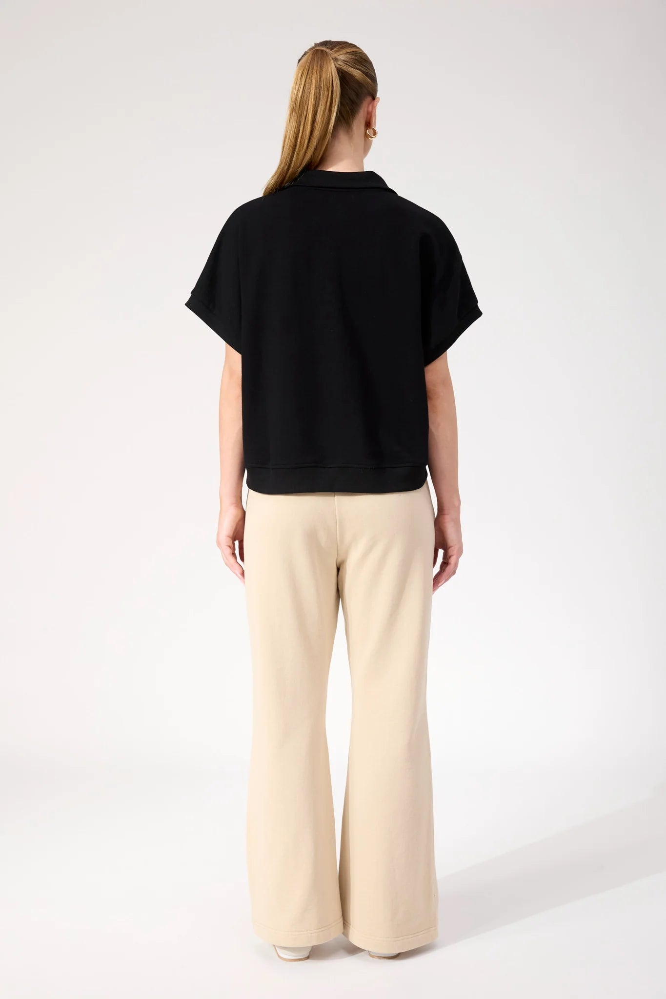 Image of Woman wearing Haven Boston Crop Sweat top in black paired with pants on a plain background 