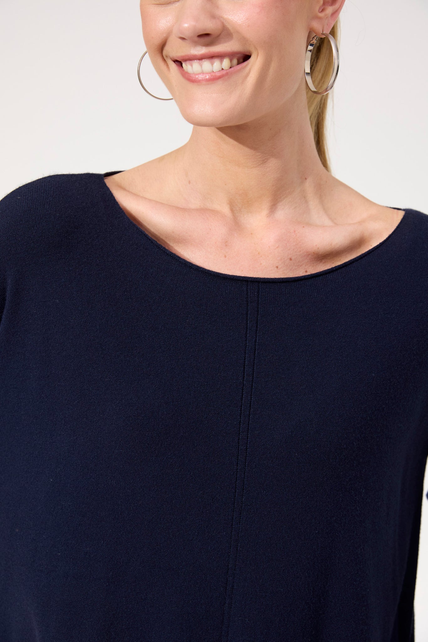 Woman wearing Haven navy jumper paired with white jeans on a plain background