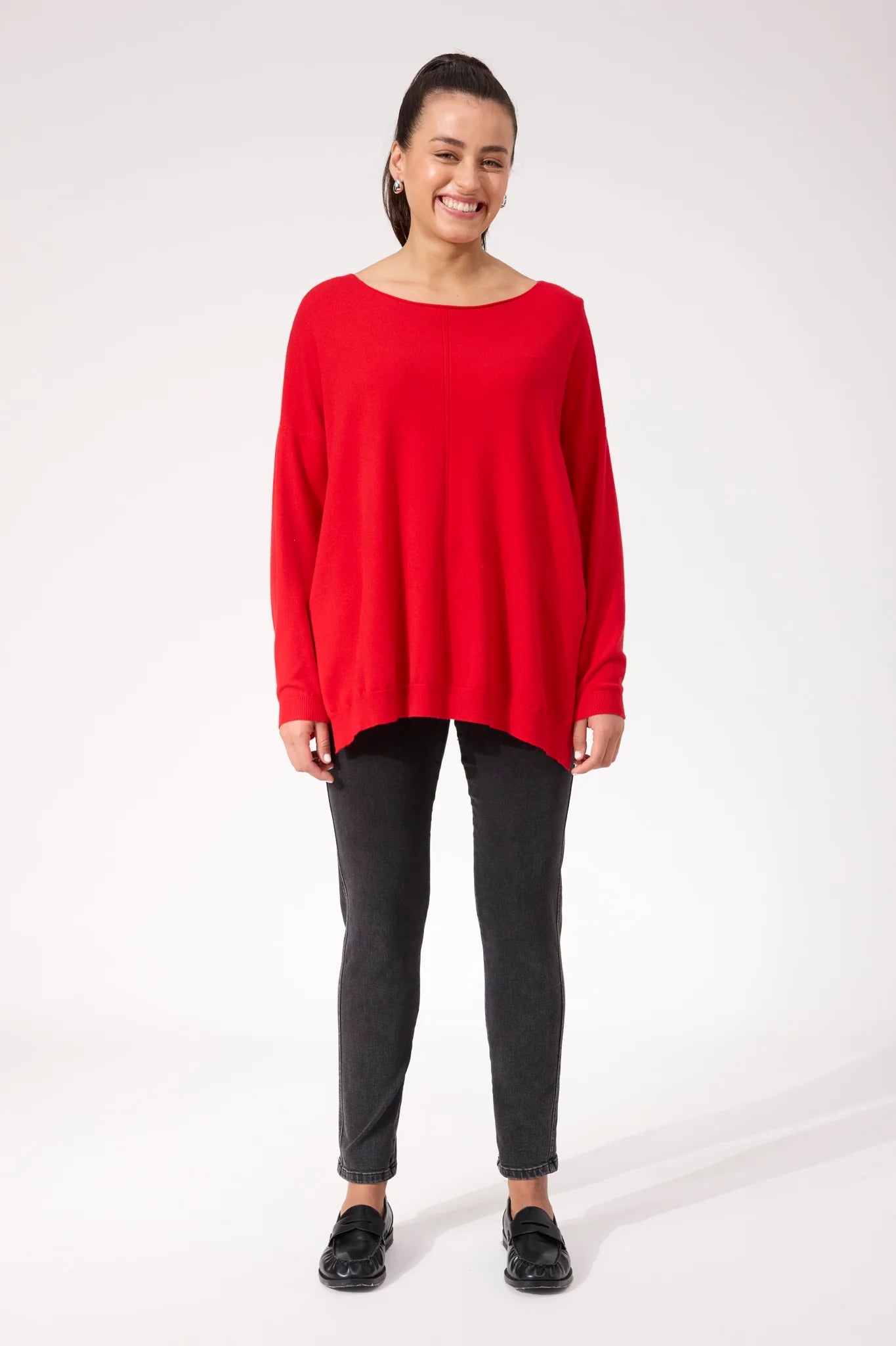 Woman wearing red Haven knit paired with black denim jeans on a plain background