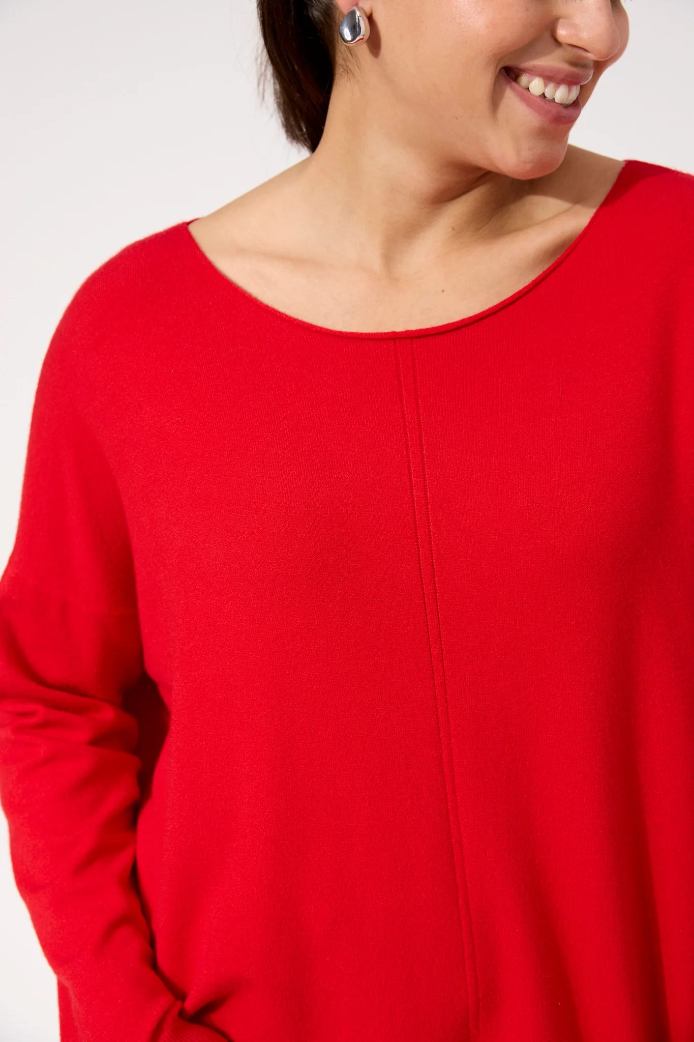 Woman wearing red Haven knit paired with black denim jeans on a plain background