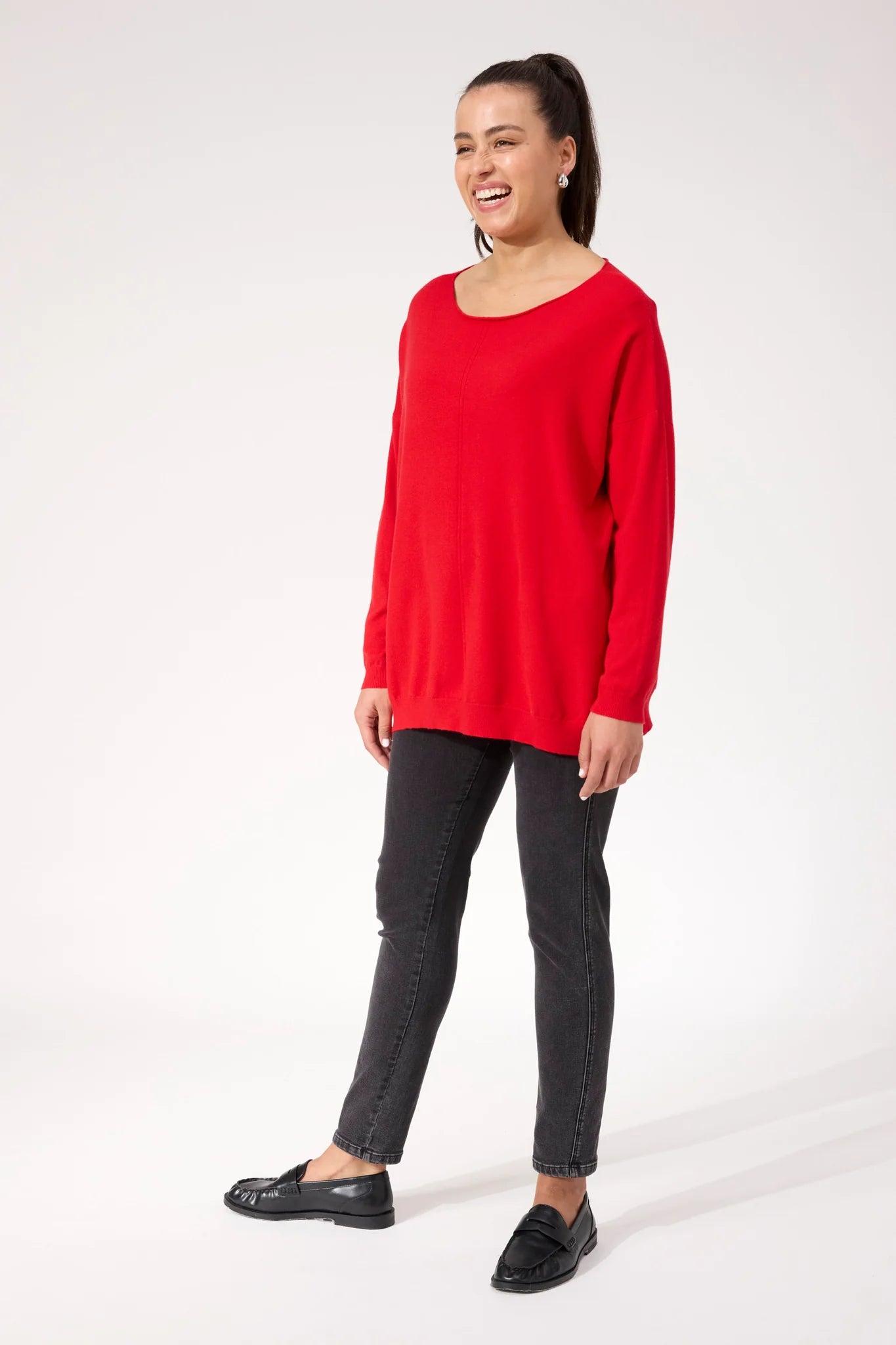 Woman wearing red Haven knit paired with black denim jeans on a plain background