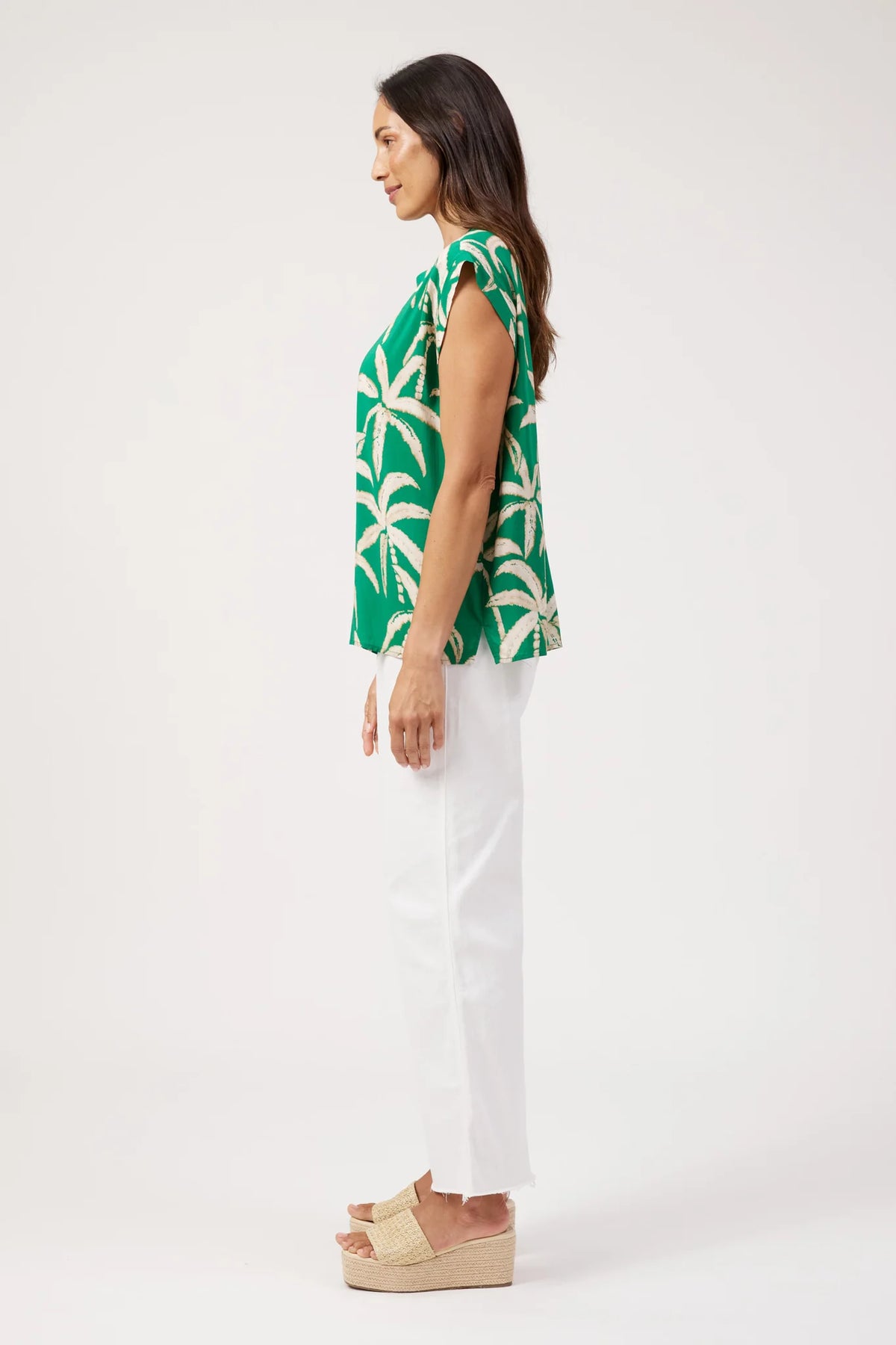 Haven printed top, green palm tree print paired with white denim pants on a plain background 