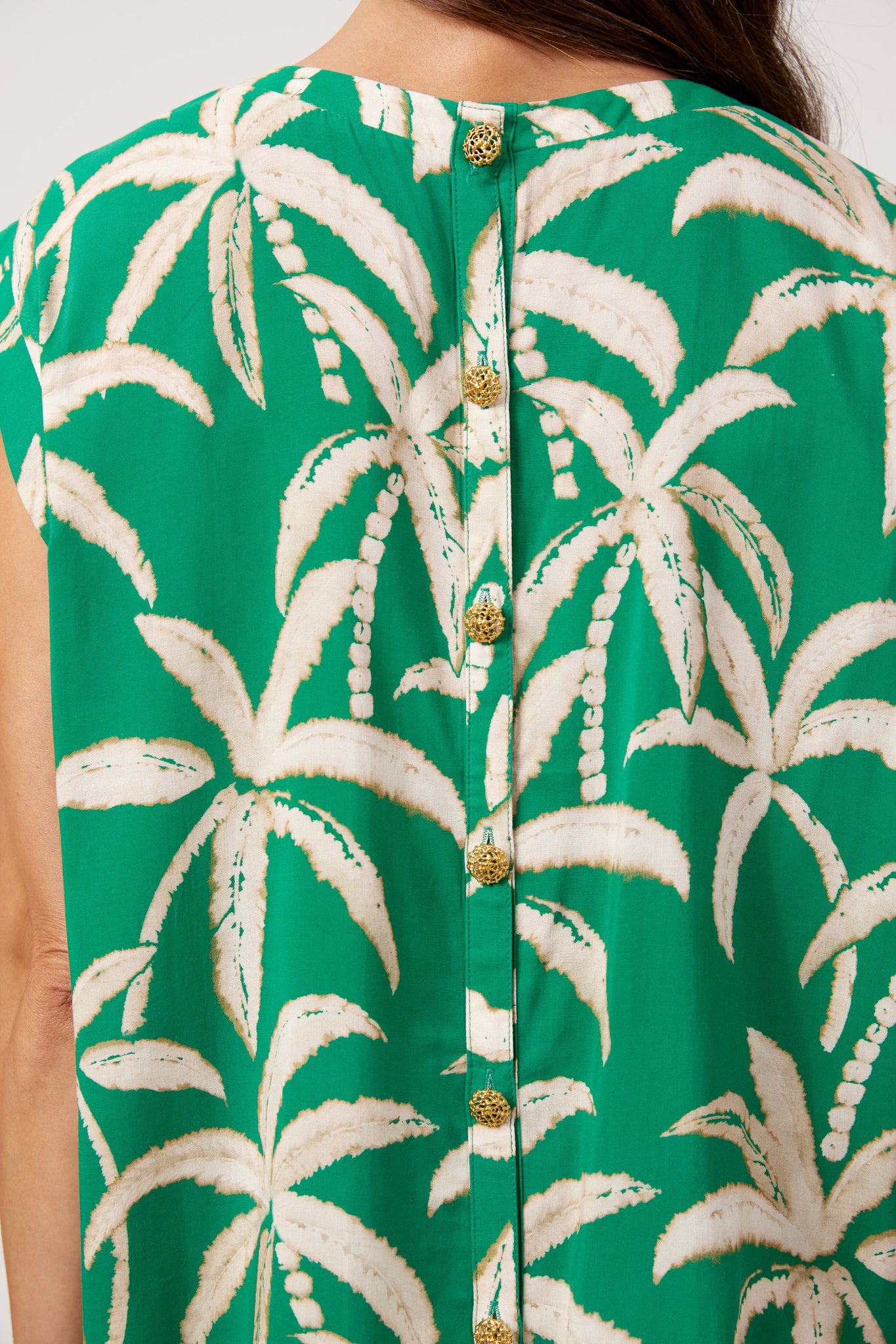 Image of Haven printed top, green palm tree print paired with white denim pants on a plain background 