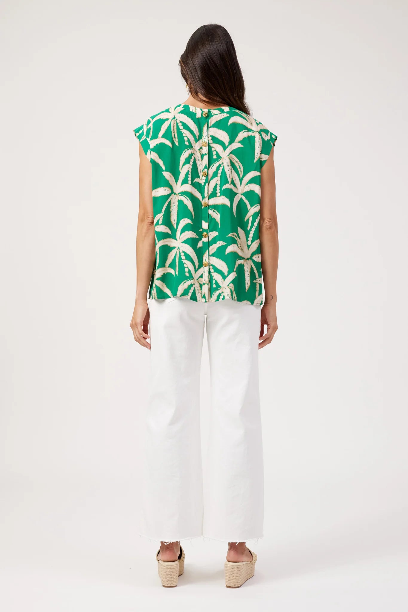 Image of Haven printed top, green palm tree print paired with white denim pants on a plain background 