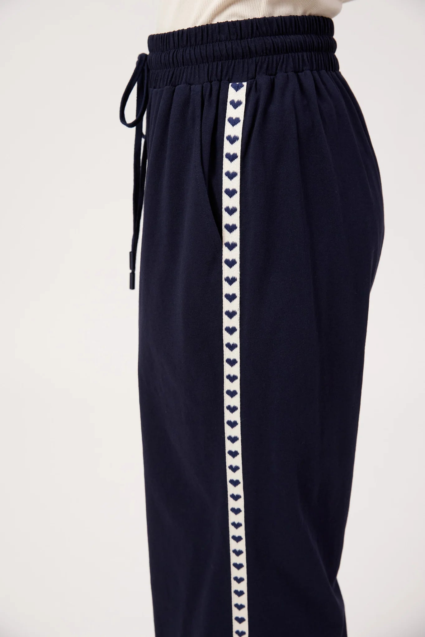 Image of A woman shown from the back wearing Haven navy wide-leg pants with a white sleeveless top, standing against a plain white studio background.