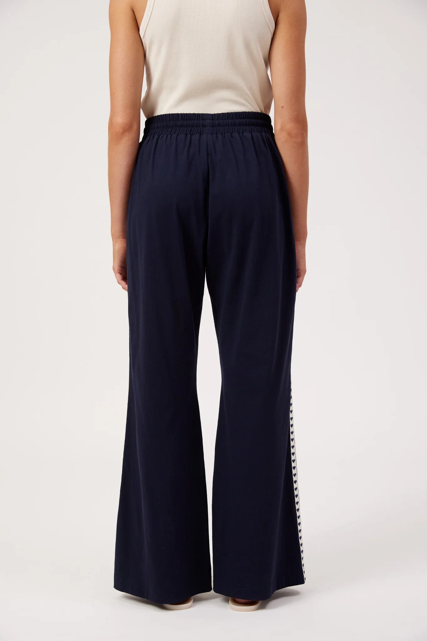 Image of A woman shown from the back wearing Haven navy wide-leg pants with a white sleeveless top, standing against a plain white studio background.