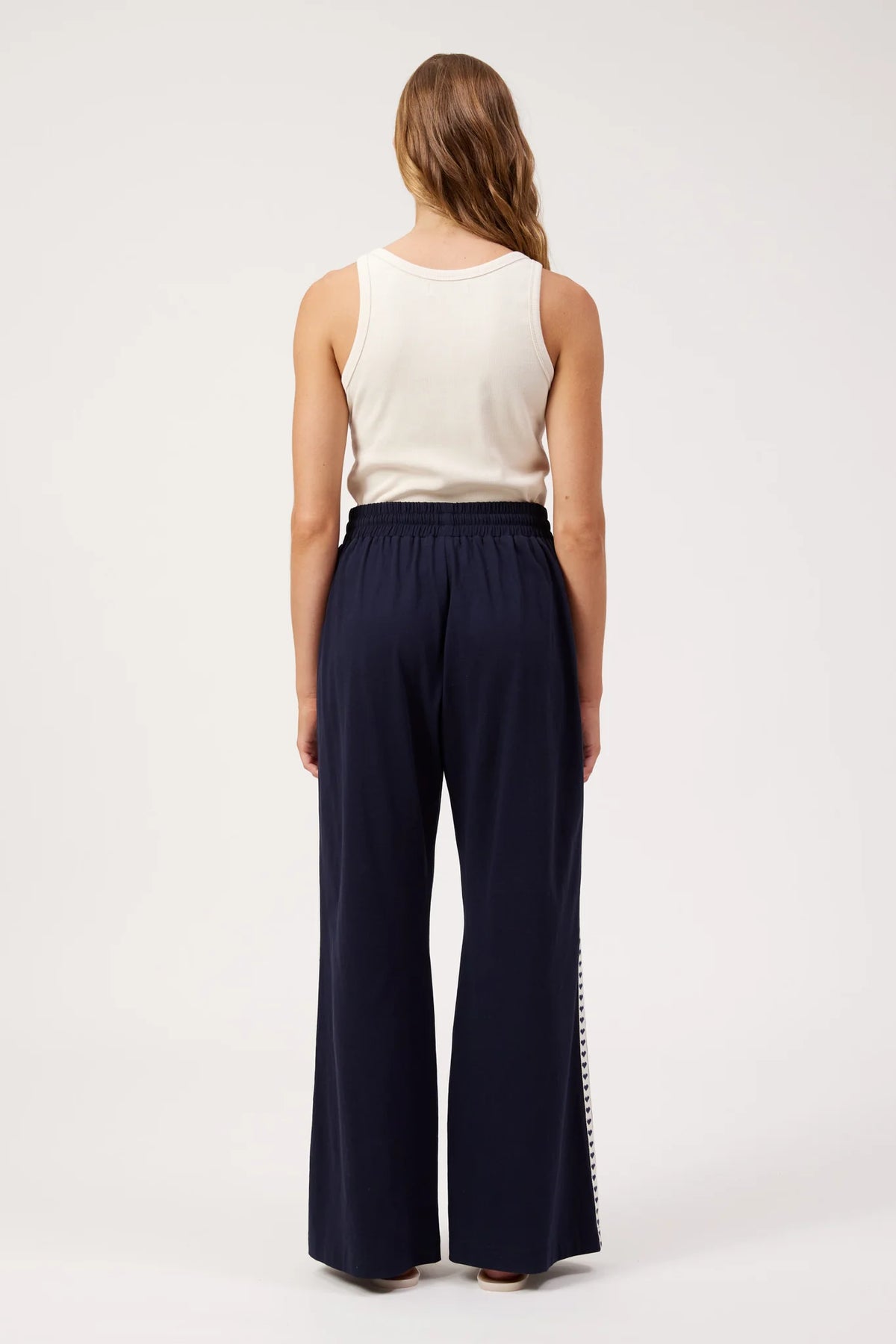 A woman shown from the back wearing Haven navy wide-leg pants with a white sleeveless top, standing against a plain white studio background.