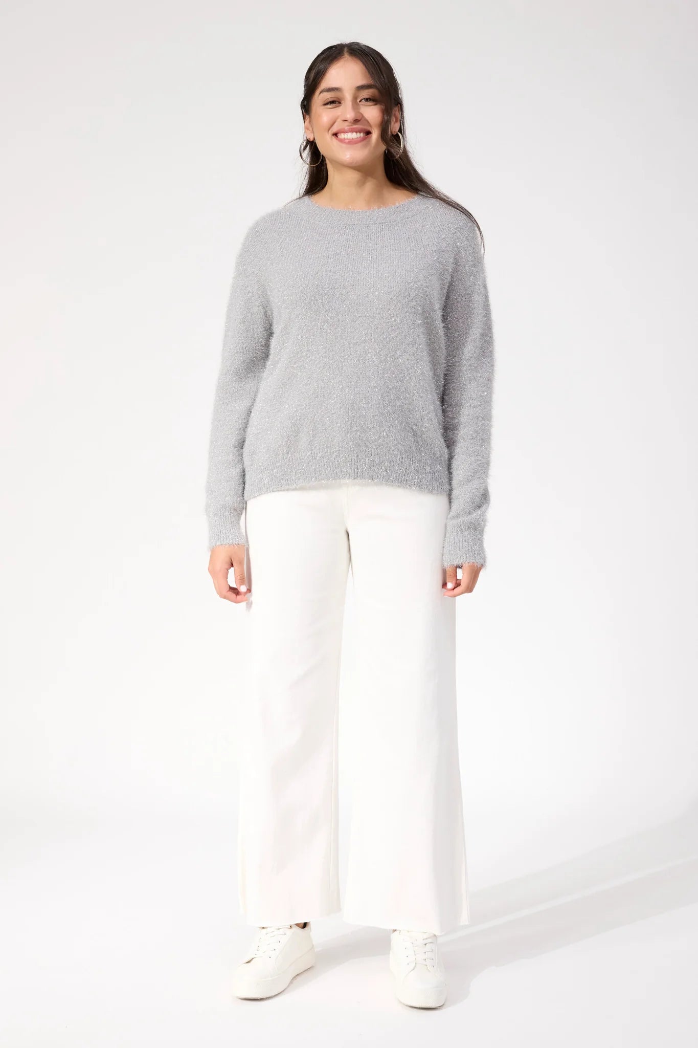 Woman wearing Haven knit paired with white denim jeans on a plain background