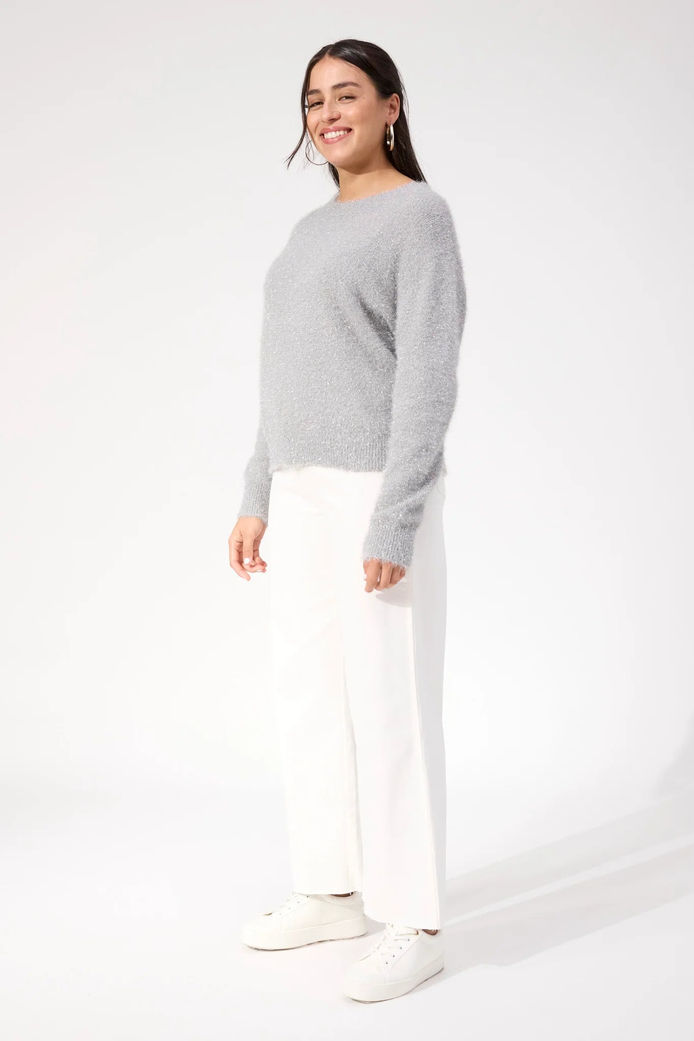 Woman wearing Haven knit paired with white denim jeans on a plain background