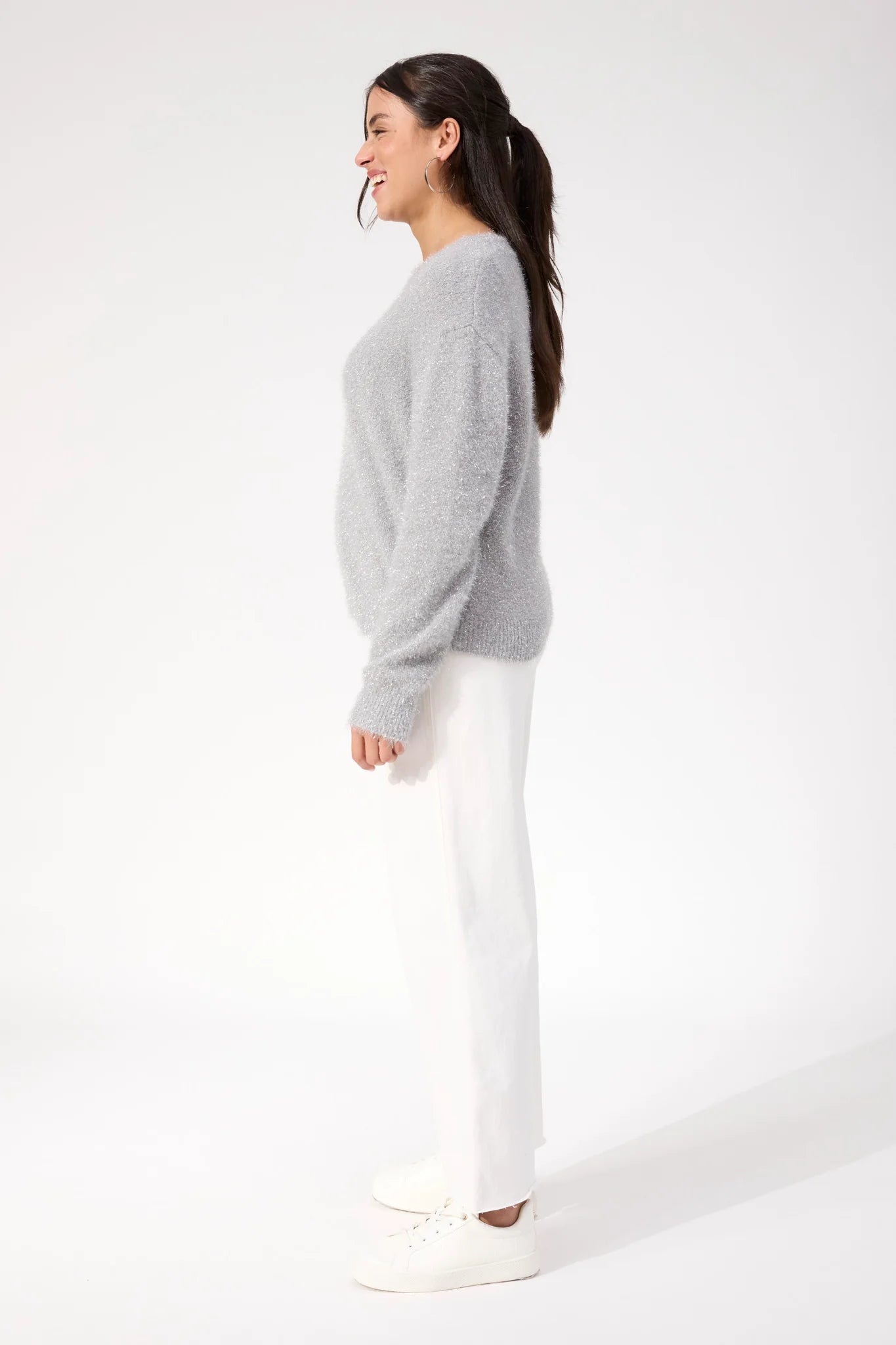 Image of Woman wearing Haven knit paired with white denim jeans on a plain background