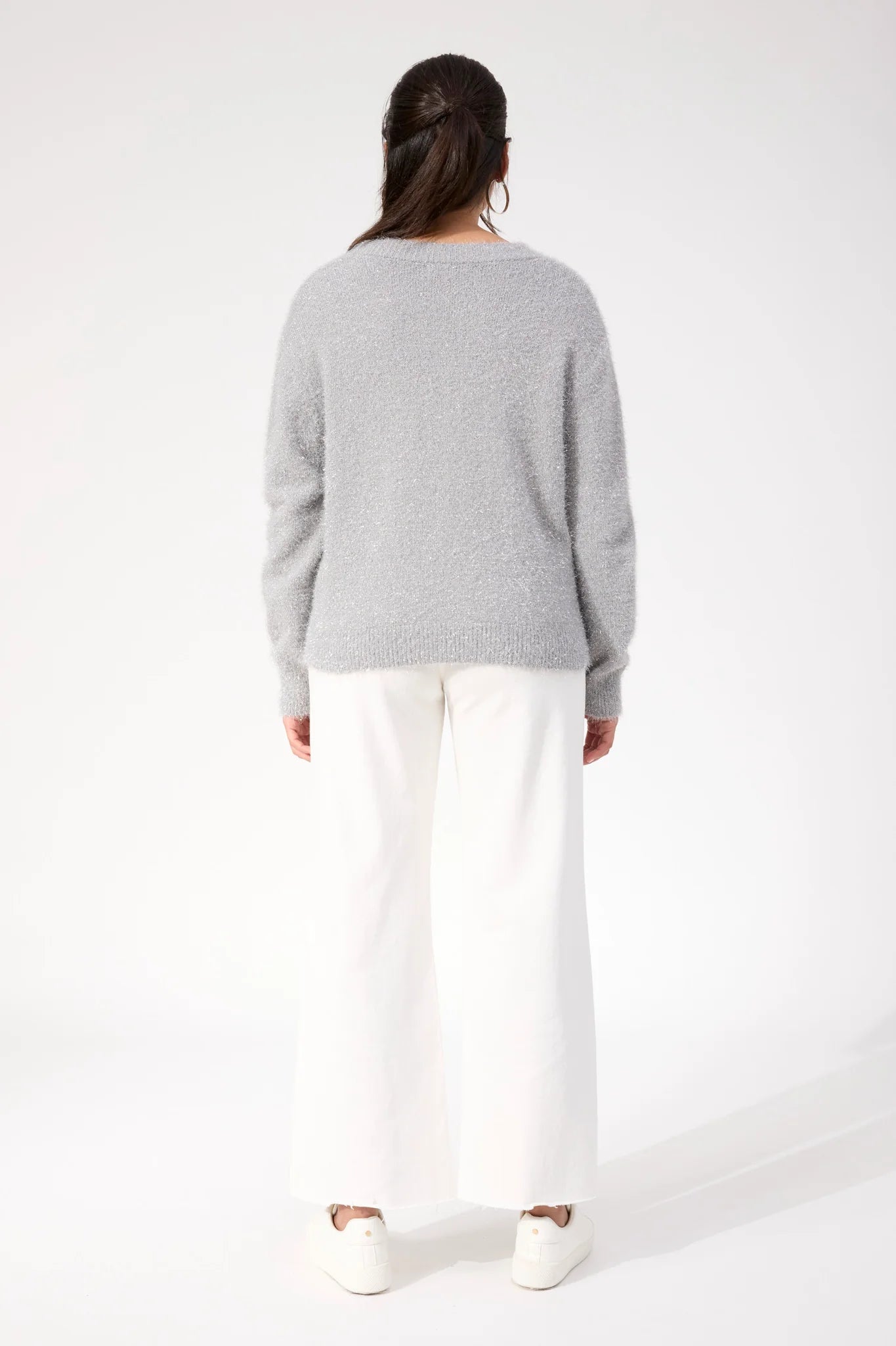 Image of Woman wearing Haven knit paired with white denim jeans on a plain background