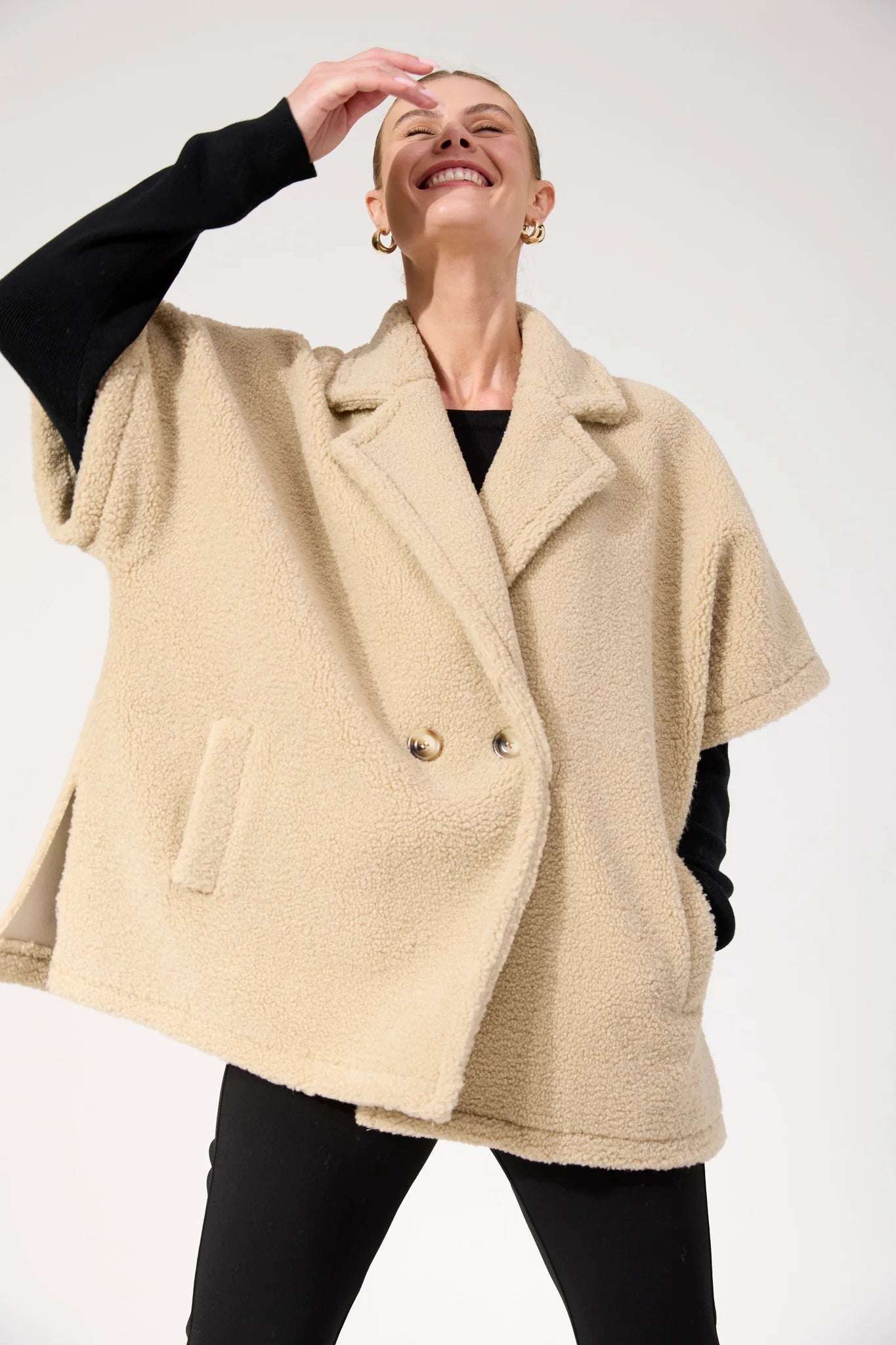 Woman wearing Haven oversized vest in a natural colour paired with black pants on a plain background 