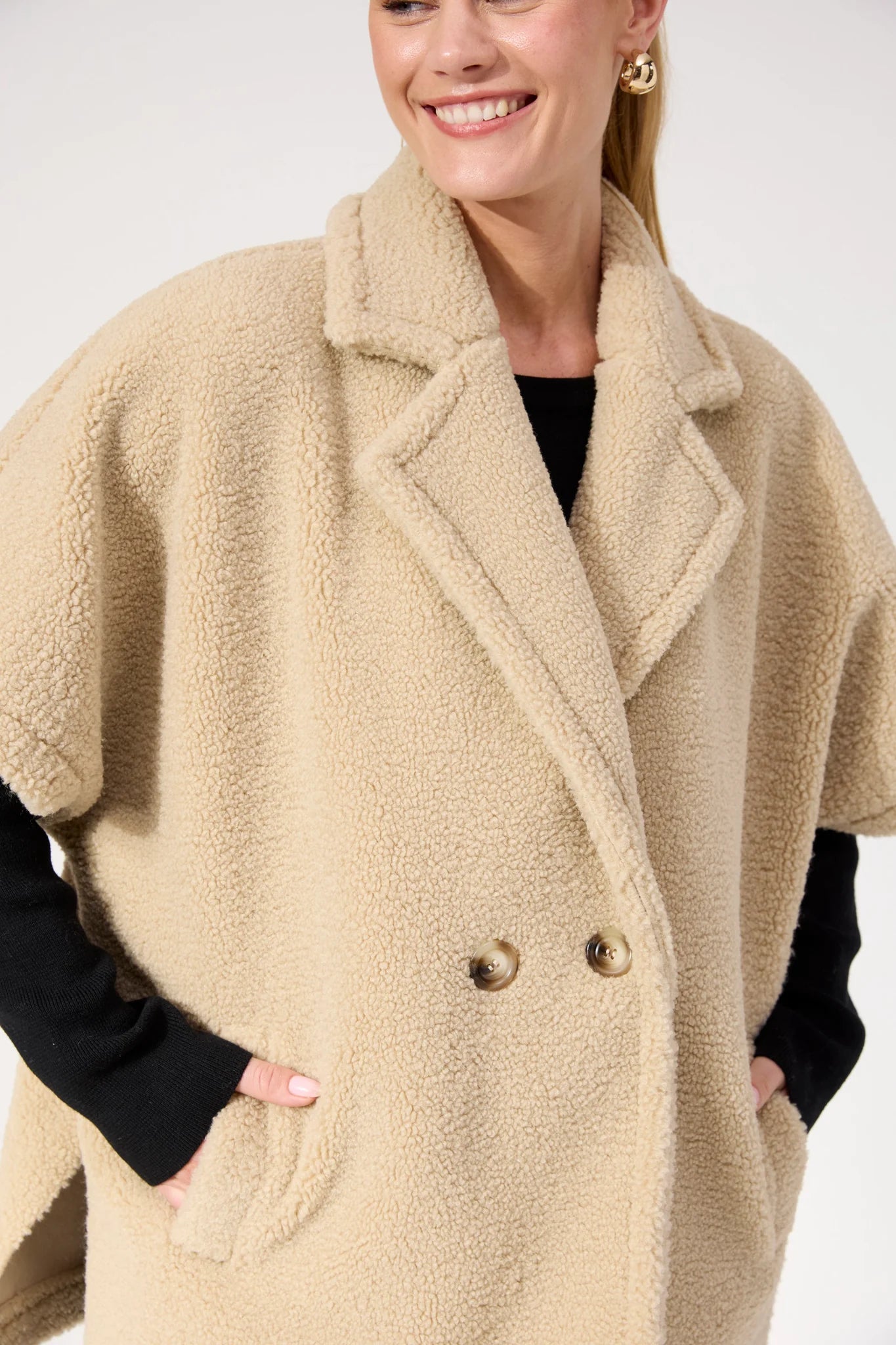 Woman wearing Haven oversized vest in a natural colour paired with black pants on a plain background 