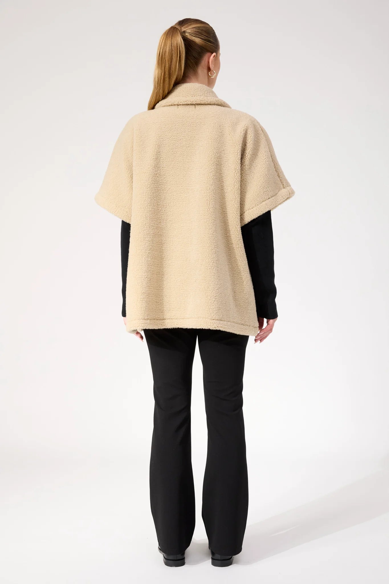 Image of Woman wearing Haven oversized vest in a natural colour paired with black pants on a plain background 