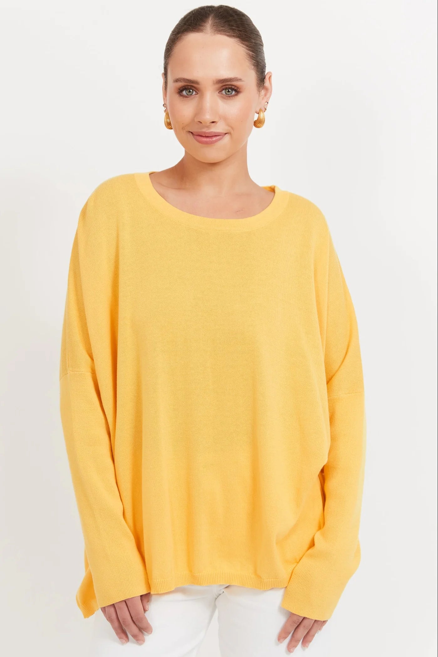 Image of Woman wearing a Banana coloured knit paired with white denim jeans on a plain background