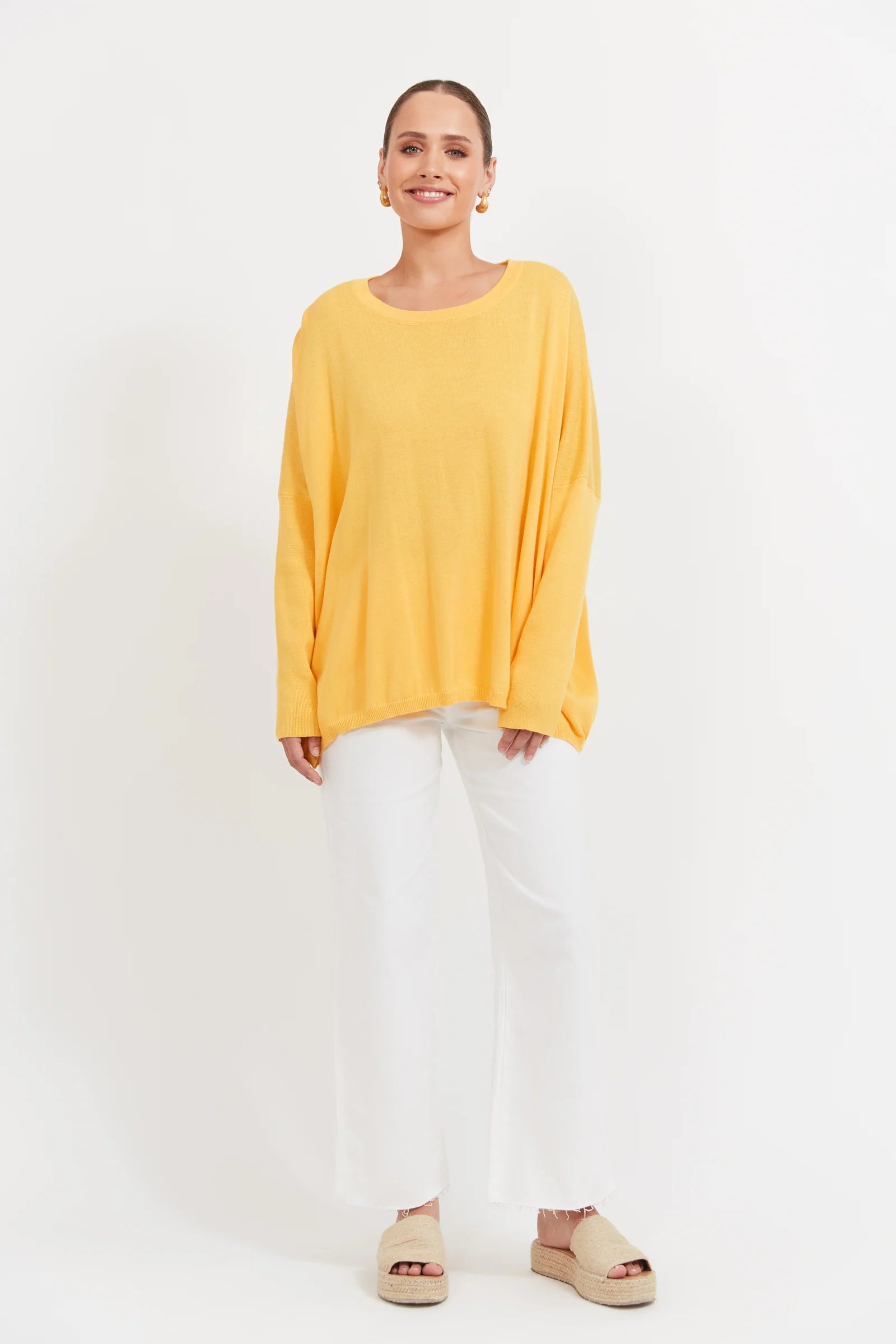Image of Woman wearing a Banana coloured knit paired with white denim jeans on a plain background